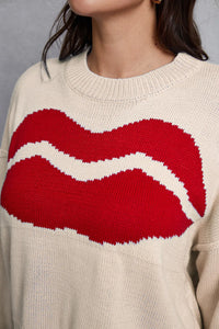 Beige sweater with a large red and white abstract design on a neutral background