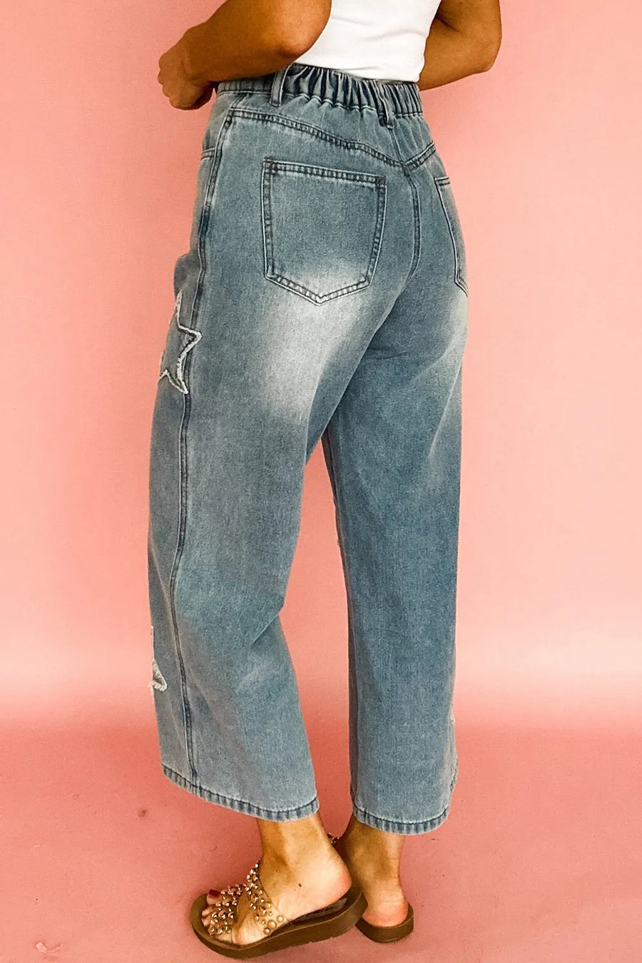 Person wearing blue jeans on a pink background