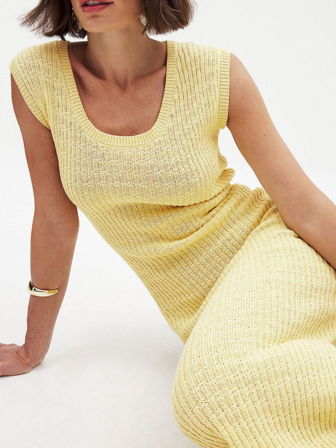 Woman wearing a yellow sleeveless dress on a white background