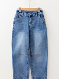 Blue jeans hanging on a wooden hanger against a white background
