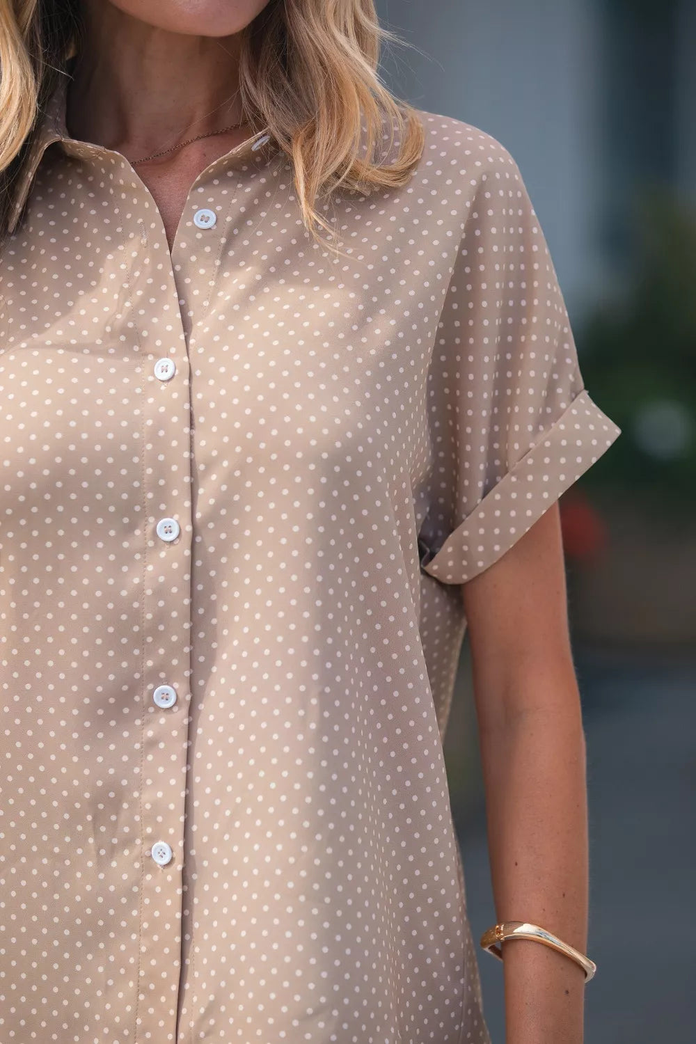 Close-up of a person wearing a brown polka dot shirt with a blurred background