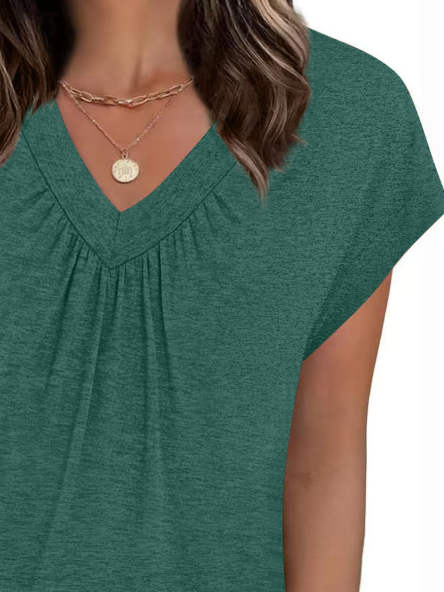 Green short-sleeve top worn by a person on a white background