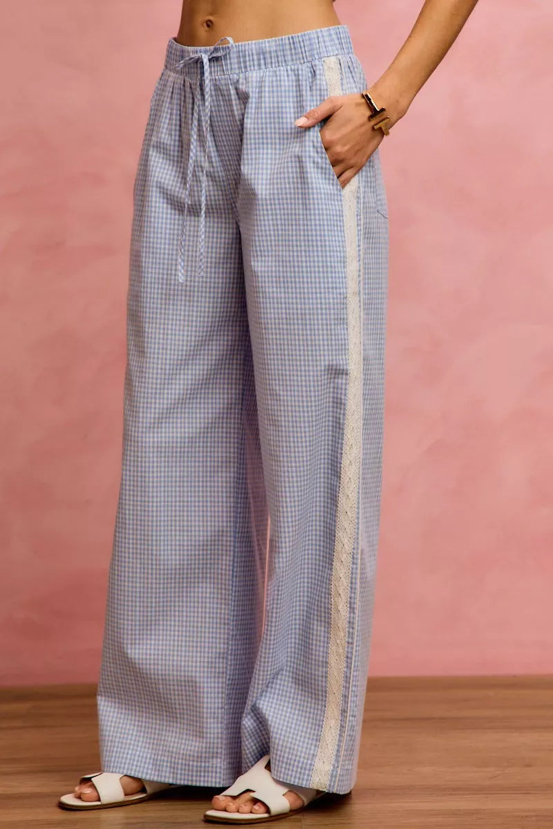 Person wearing blue checkered pants with a white stripe on a pink background