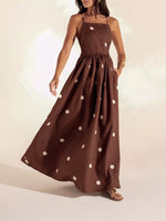Woman wearing a brown dress with white polka dots on a plain background