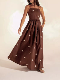 Woman wearing a brown dress with white polka dots on a plain background