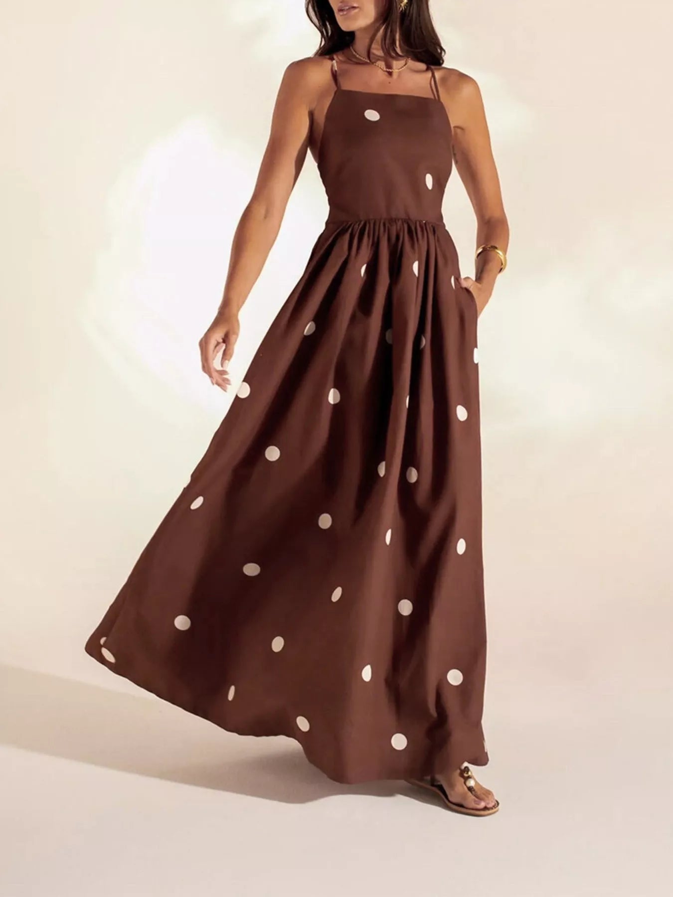 Woman wearing a brown dress with white polka dots on a plain background