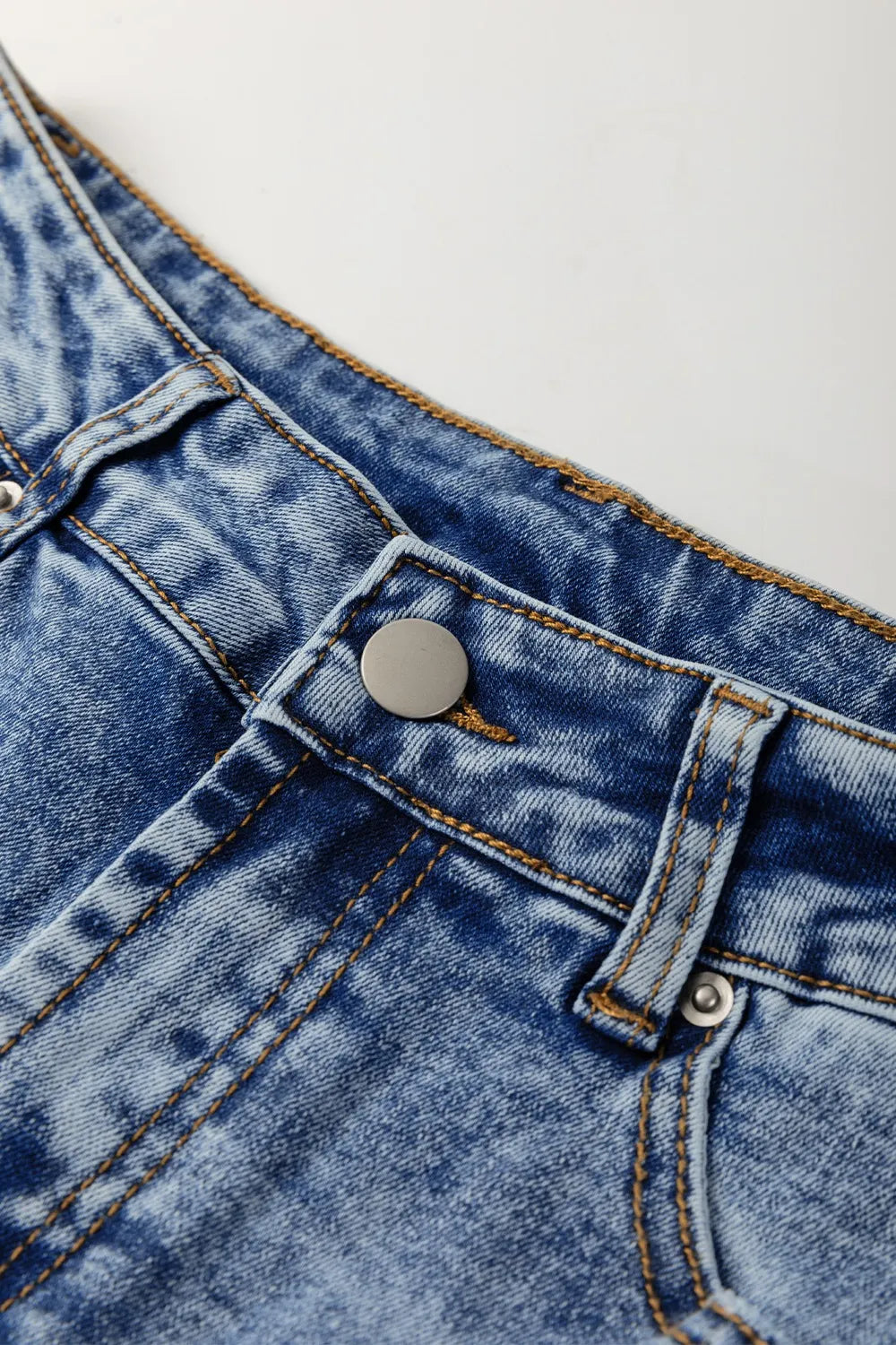 Close-up of blue denim fabric with a button on a white background