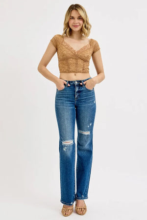 Woman wearing a brown top and blue jeans on a white background
