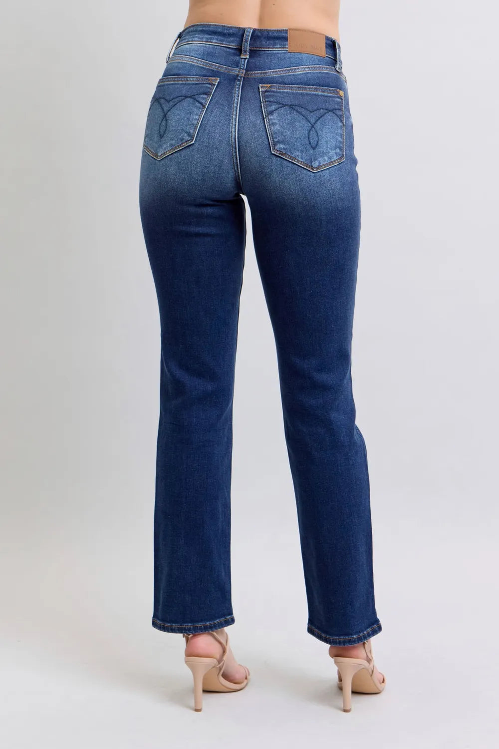 Blue jeans worn by a person on a plain background