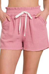 Pink shorts with a white drawstring on a neutral background