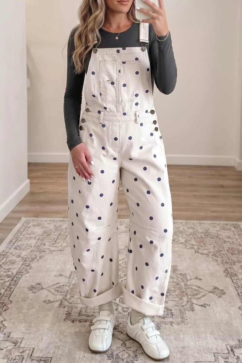 Person wearing a white overalls with black polka dots indoors.