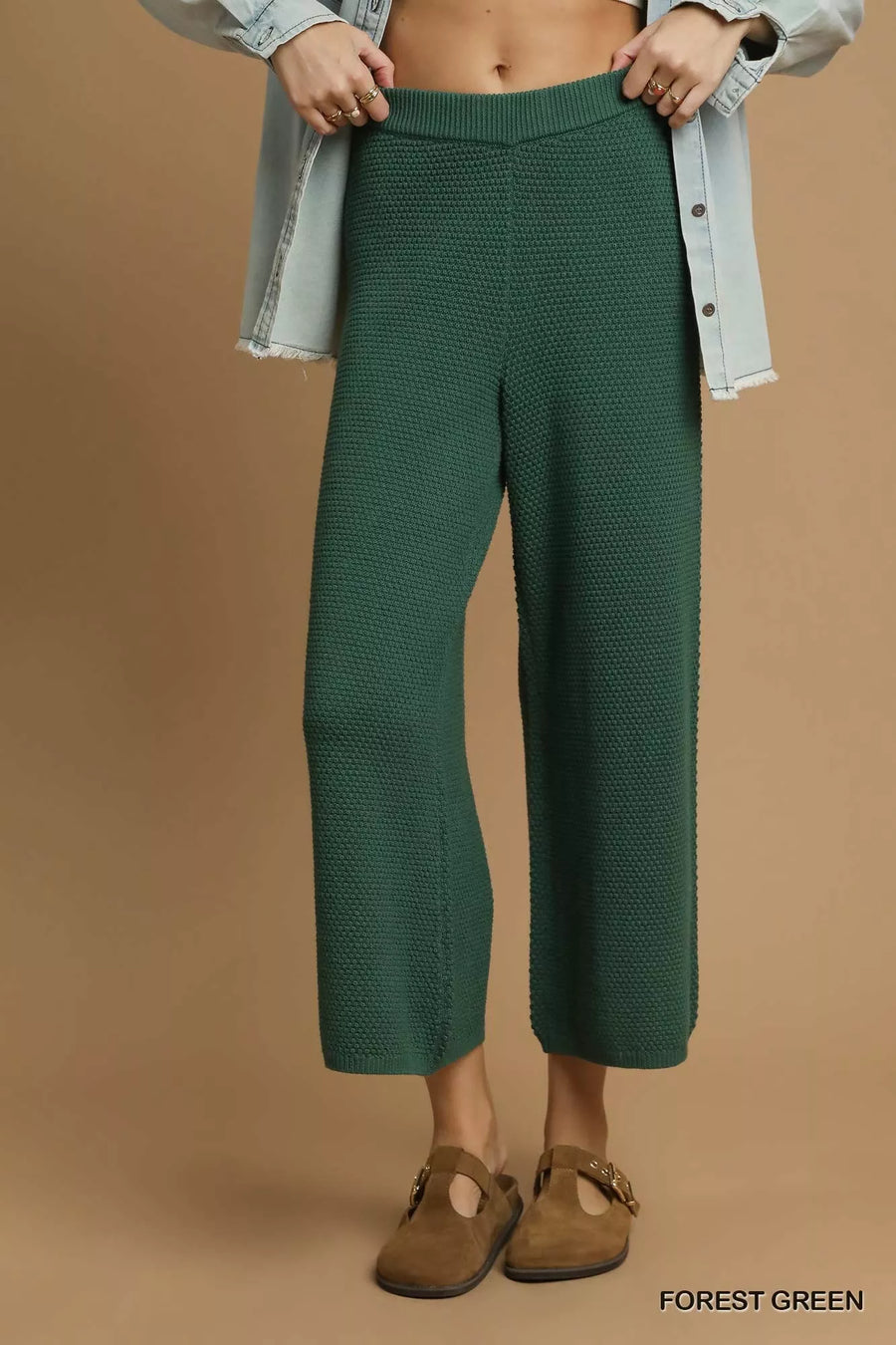 Person wearing forest green textured pants on a brown background