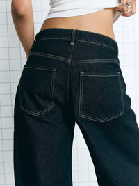 Dark blue jeans worn by a person on a white background