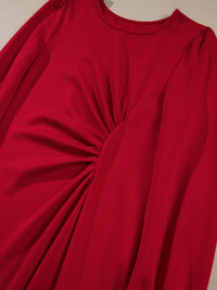 Red long-sleeve top with a knot detail on a beige background