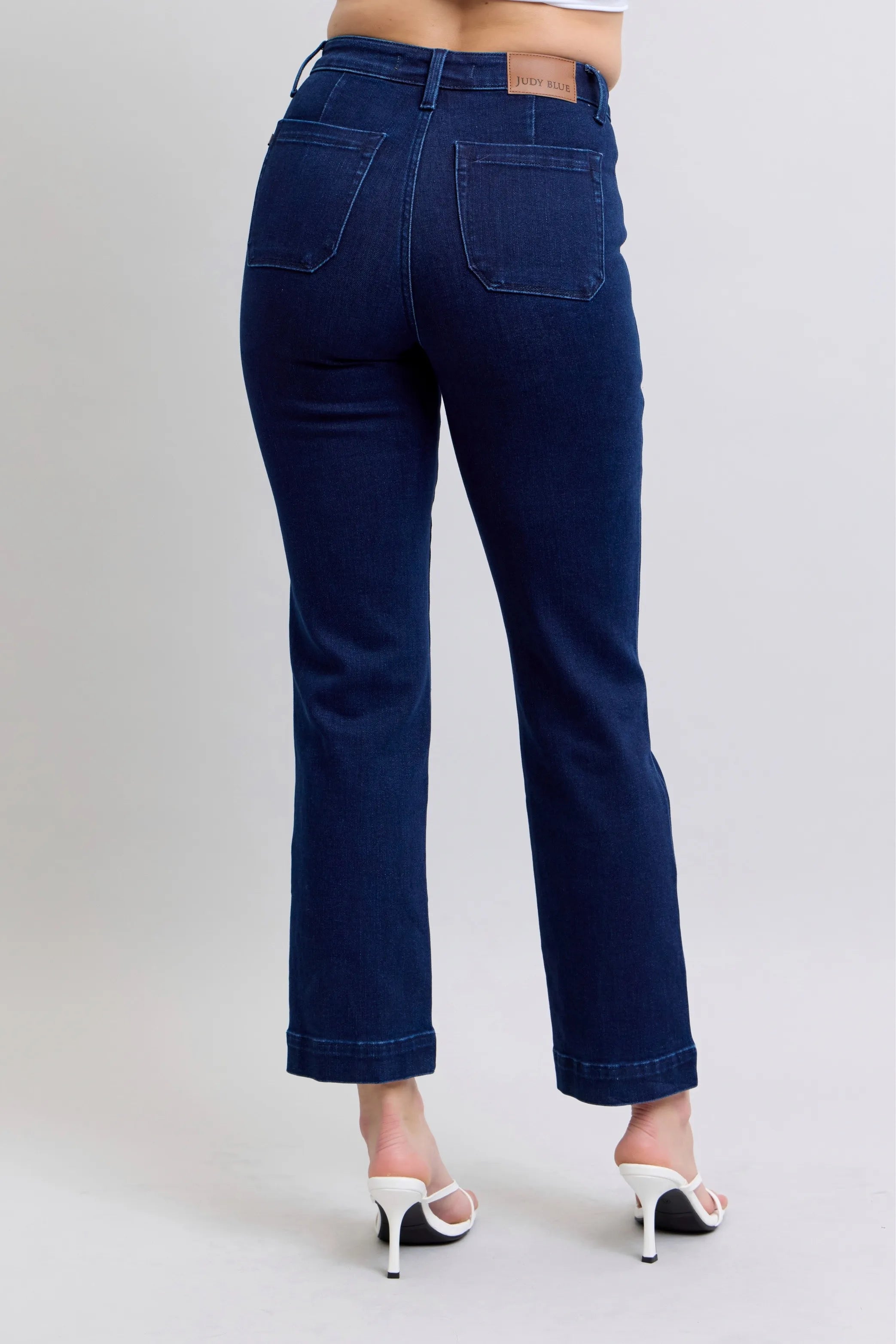 Navy blue jeans worn by a person on a plain background