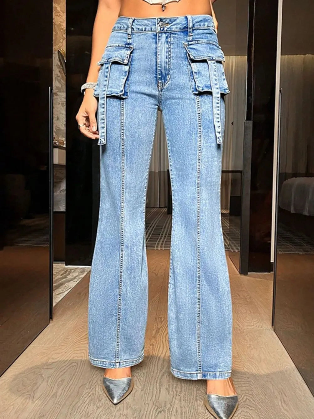 Person wearing high-waisted blue jeans with cargo pockets in a room.