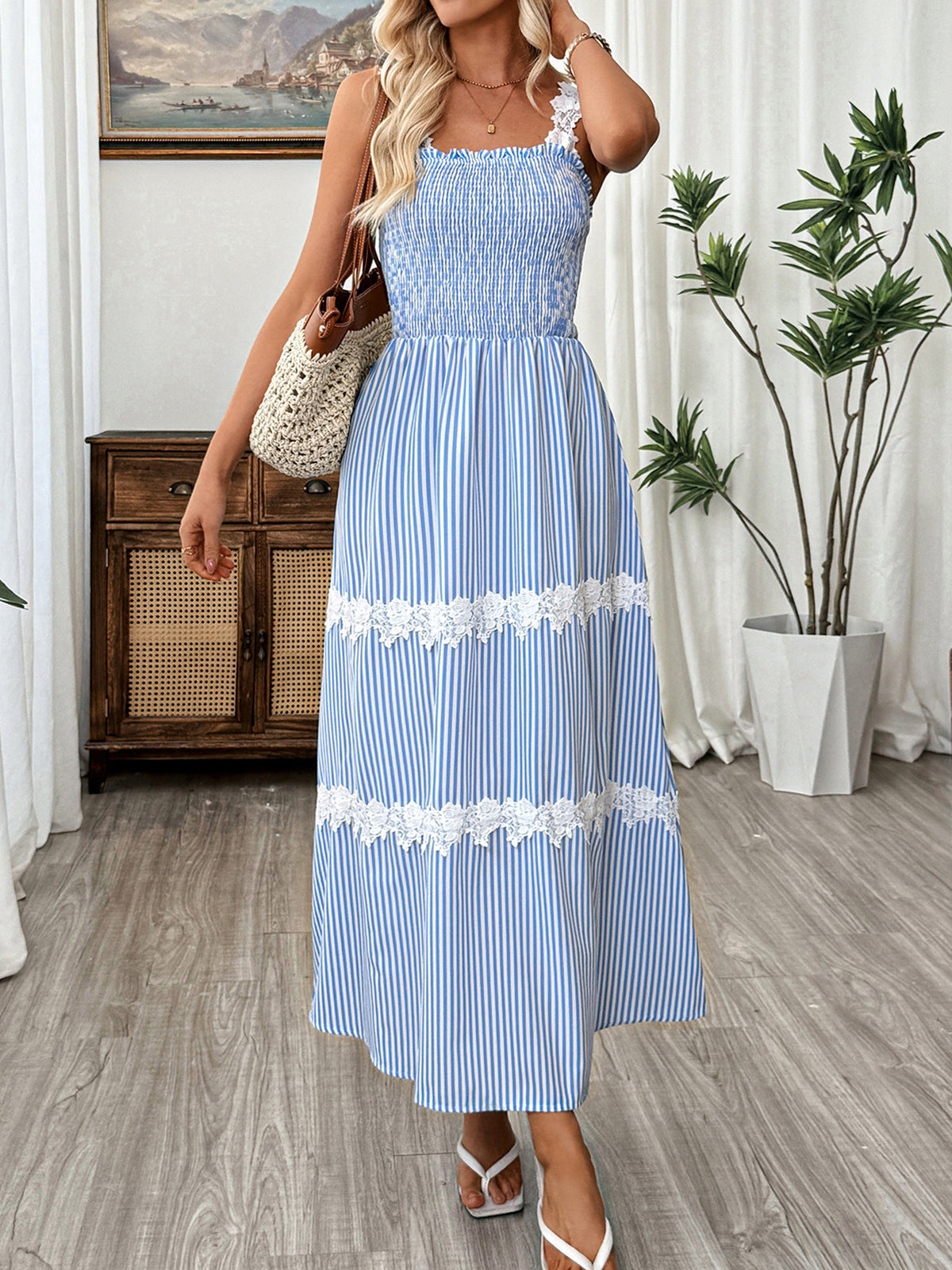 Woman wearing a blue and white striped dress with floral details indoors.