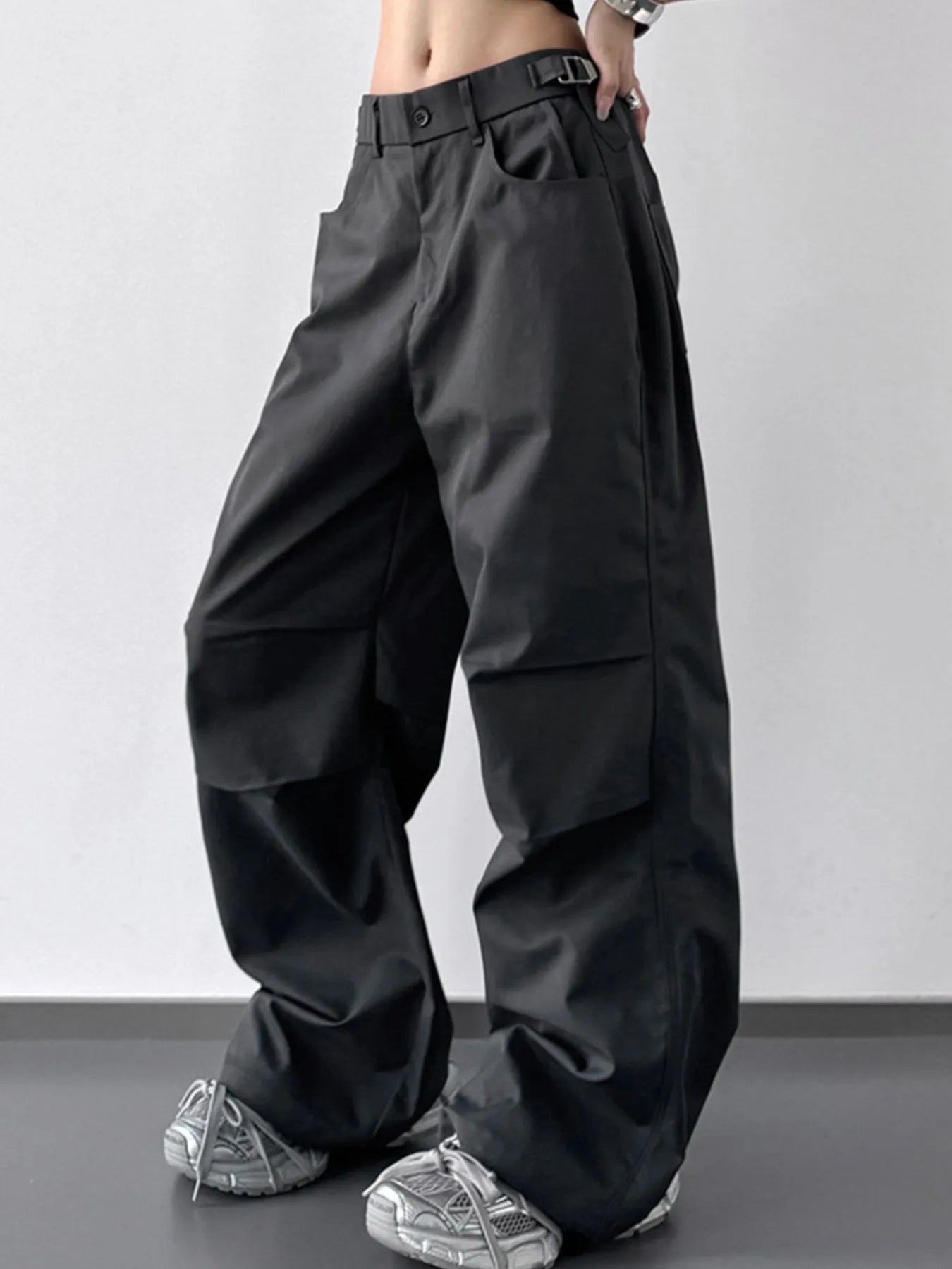 Person wearing black wide-leg pants with a plain background