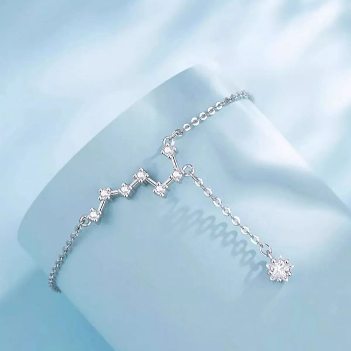 Silver bracelet with star-shaped charms on a light blue background