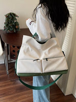 Person holding a white duffel bag with green straps in a room.