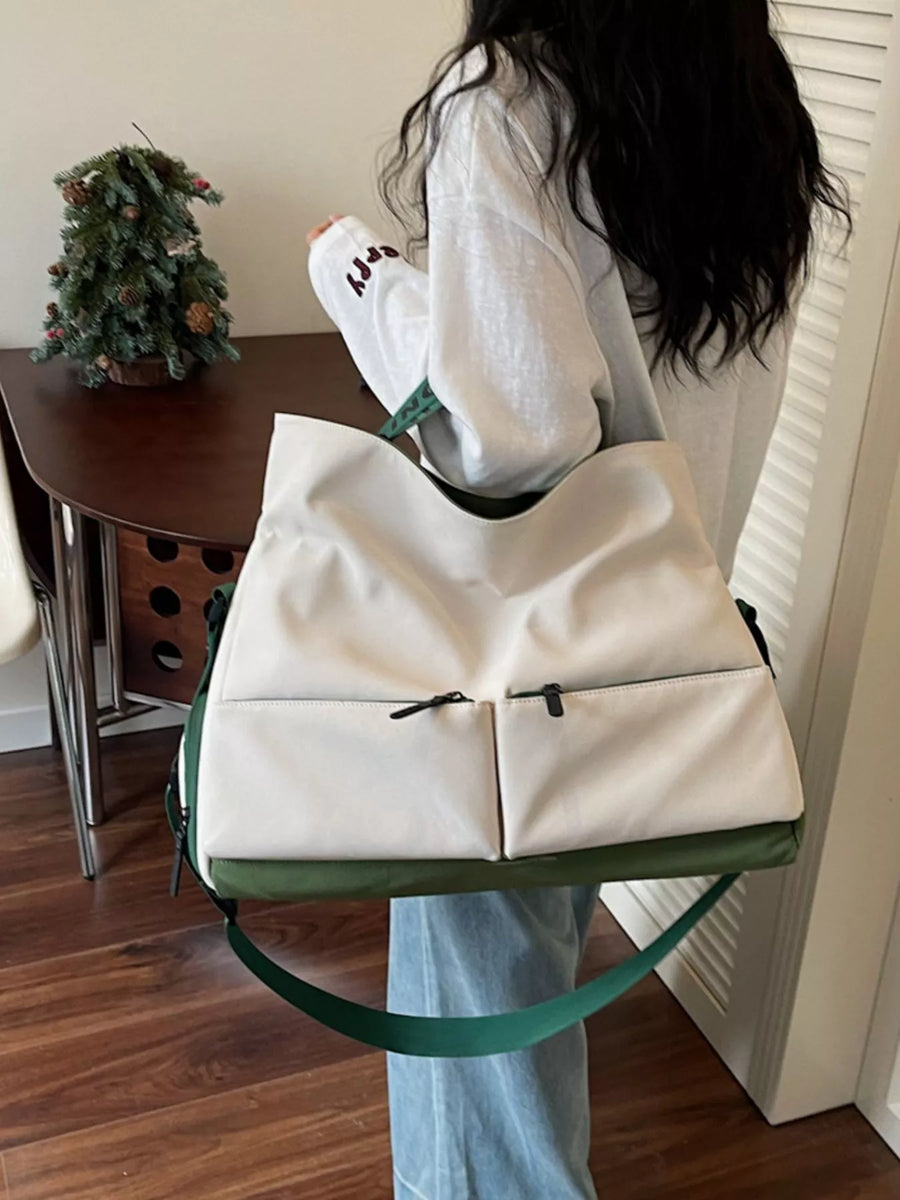 Person holding a white duffel bag with green straps in a room.