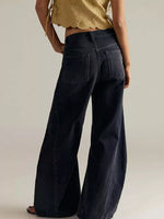 Person wearing black wide-leg jeans and a gold top on a plain background