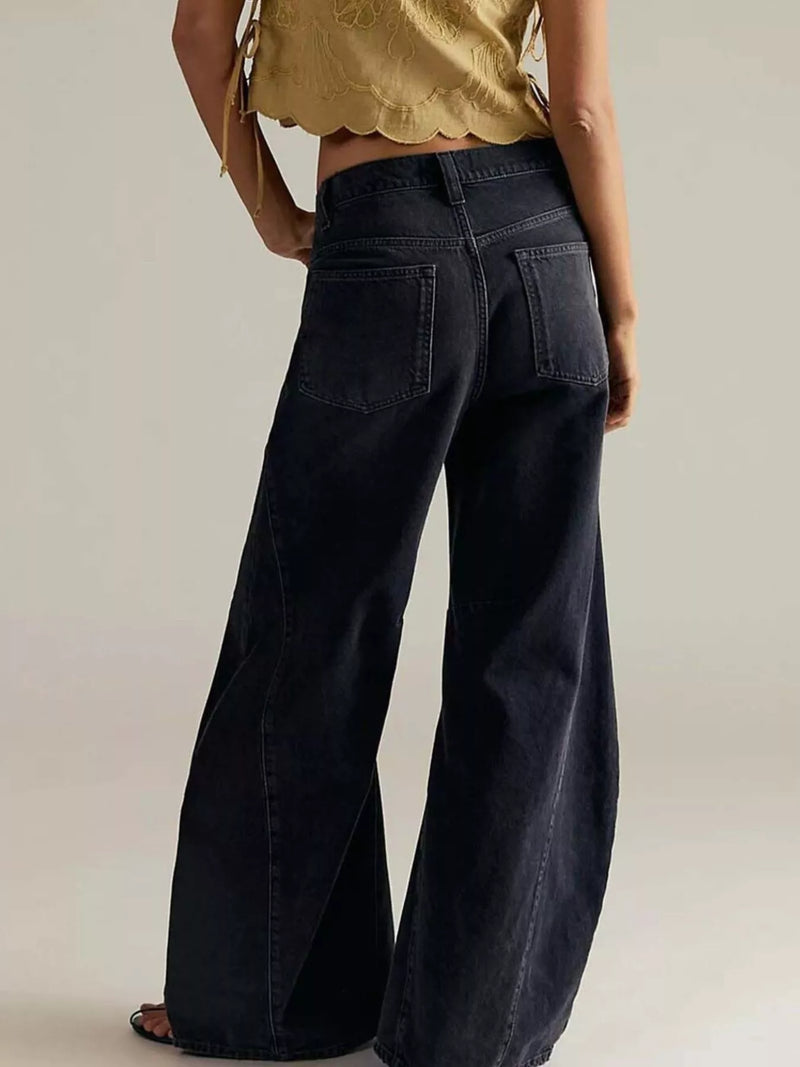Person wearing black wide-leg jeans and a gold top on a plain background