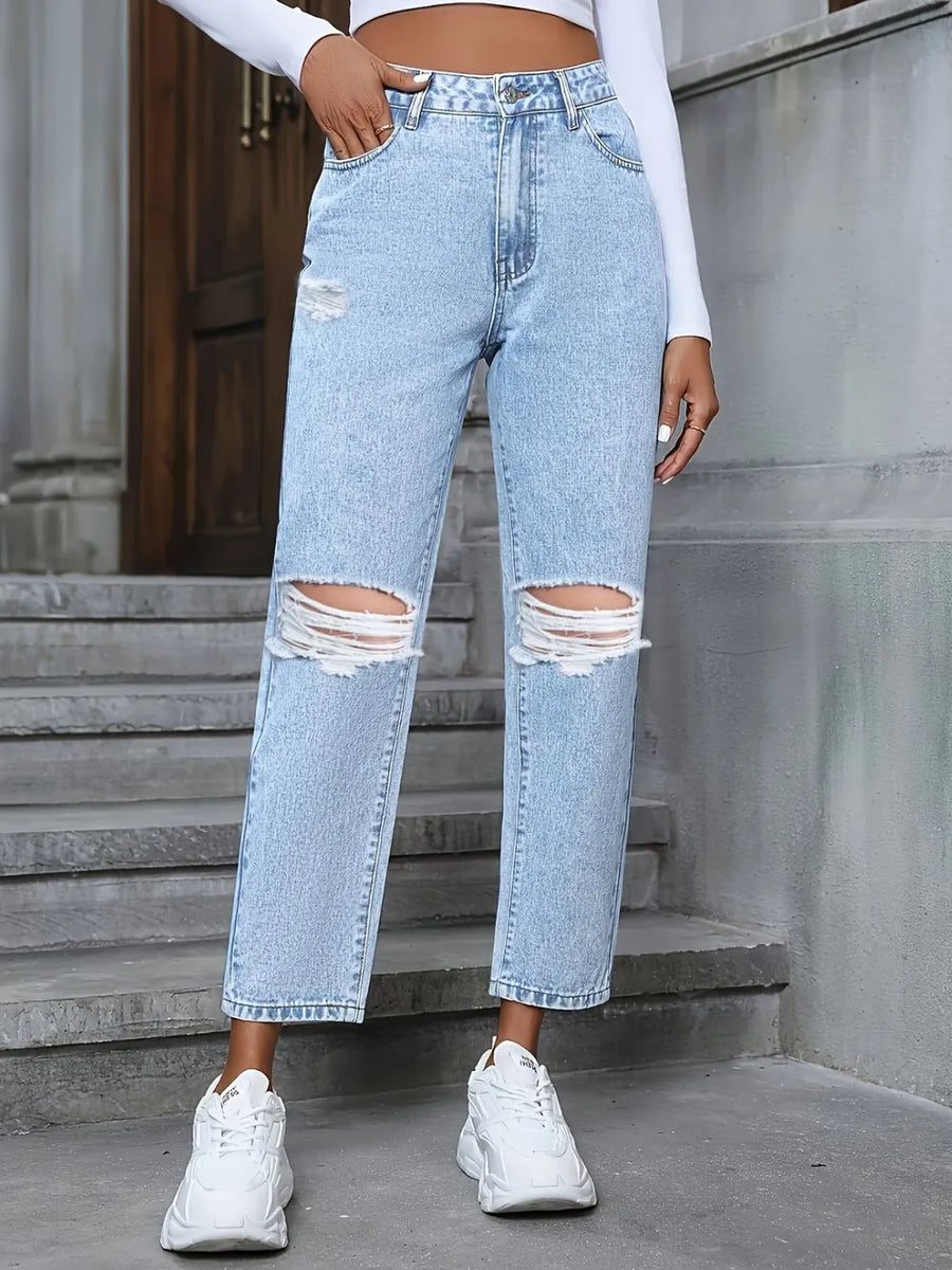 Person wearing light blue ripped jeans and white sneakers on a concrete staircase.