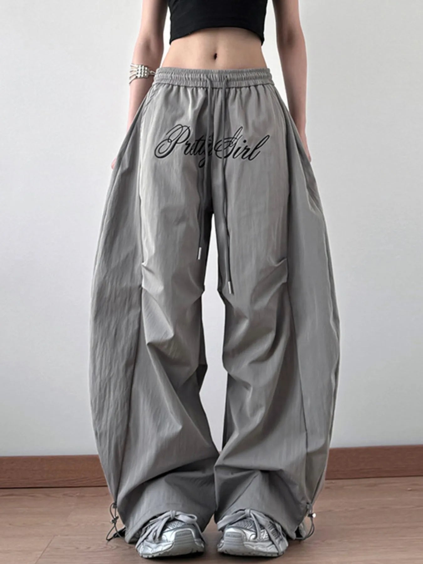 Person wearing gray wide-leg pants with 'Pussy Girl' text on a plain background