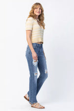 Woman wearing a striped shirt and ripped jeans on a white background