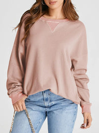 Person wearing a pink textured sweater and blue jeans on a white background