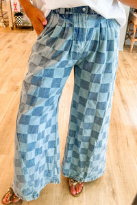 Person wearing blue checkered pants on a wooden floor.