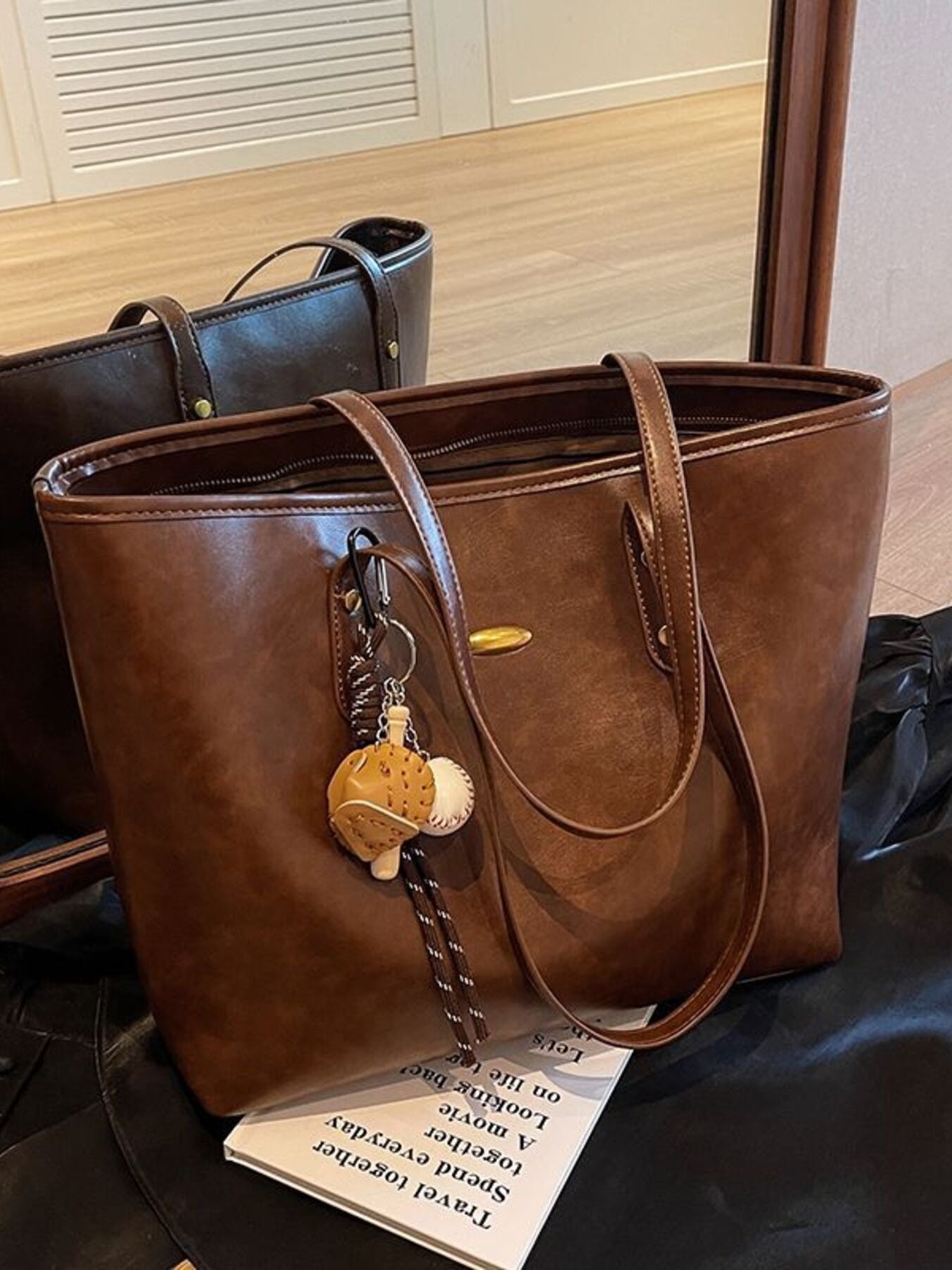 Brown leather tote bag with a keychain on a black surface