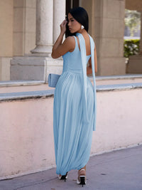 Woman in a light blue dress standing in front of classical architecture.
