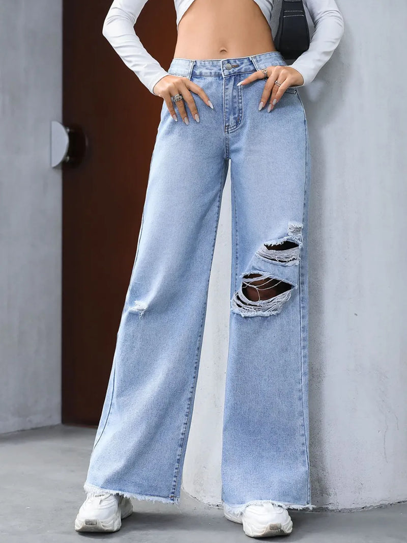 Person wearing light blue jeans with a distressed design, standing against a neutral background.
