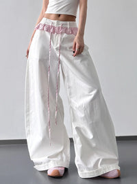 White wide-leg pants with pink waistband and trim on a plain background