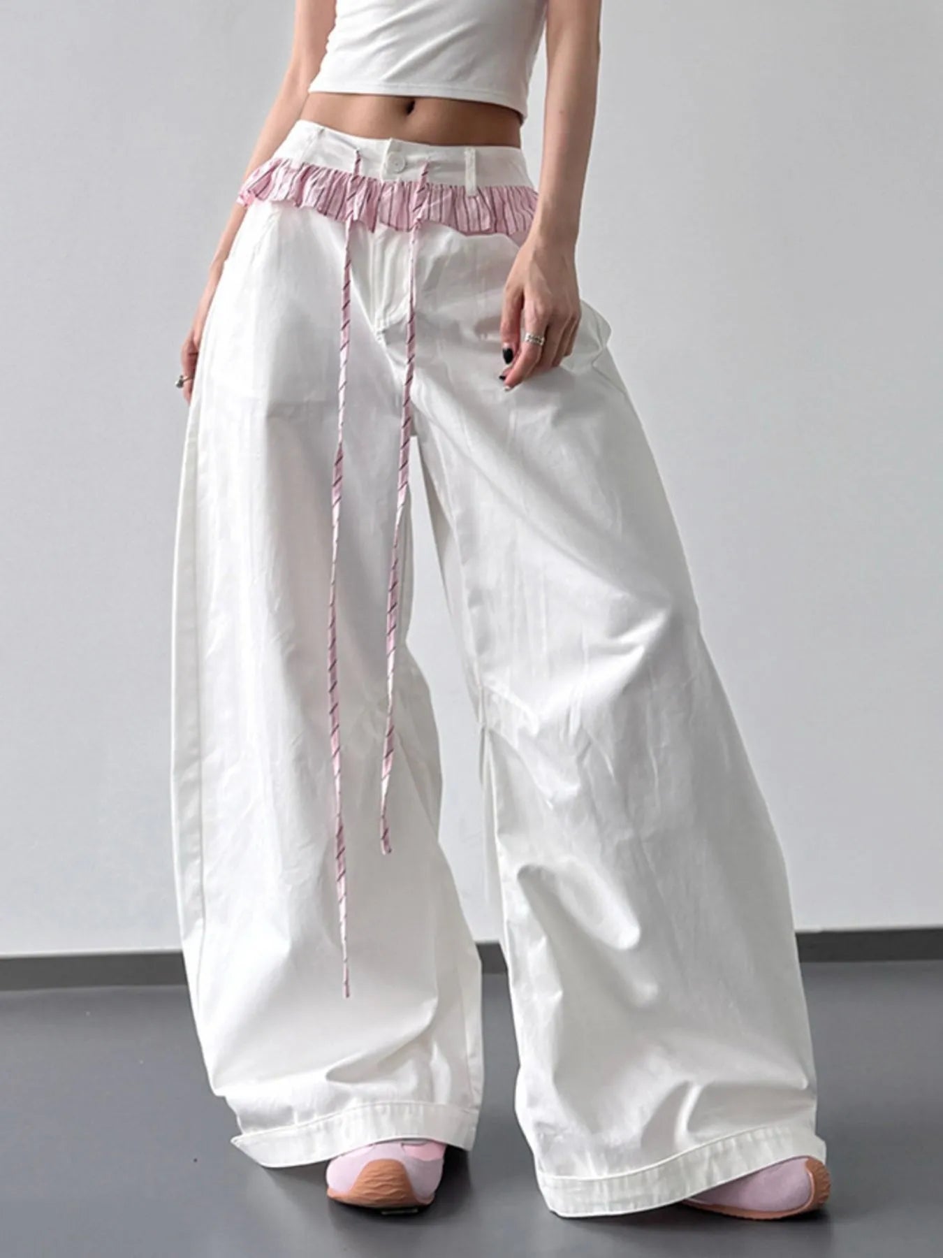 White wide-leg pants with pink waistband and trim on a plain background