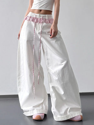 White wide-leg pants with pink waistband and trim on a plain background