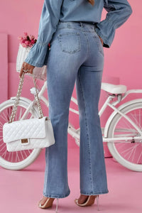 Person wearing blue jeans and a denim shirt with a white handbag and bicycle in the background.