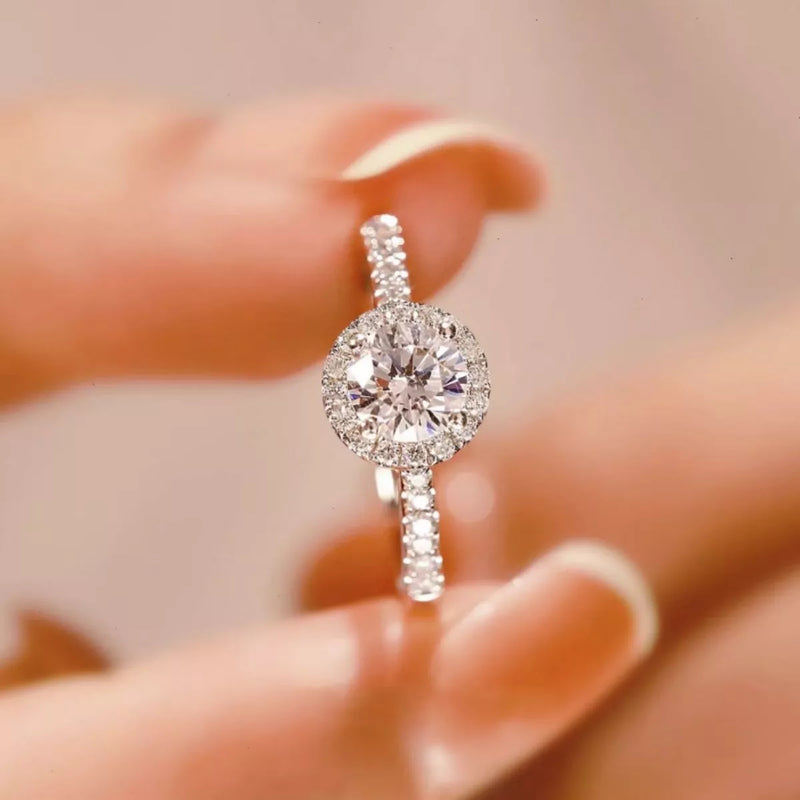 Diamond ring held between fingers with a blurred background