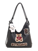 Black handbag with teddy bear and 'STRONG' text on a white background