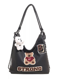 Black handbag with teddy bear and 'STRONG' text on a white background