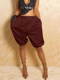 Person wearing maroon harem pants and a black crop top against a beige background