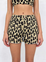 Person wearing leopard print shorts and top on a white background