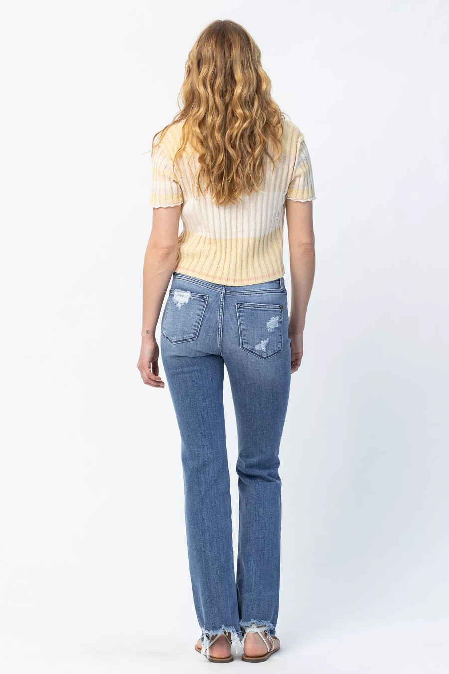Person wearing blue jeans and a striped shirt on a white background