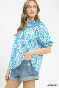 Woman wearing a blue and white patterned top with denim shorts on a white background