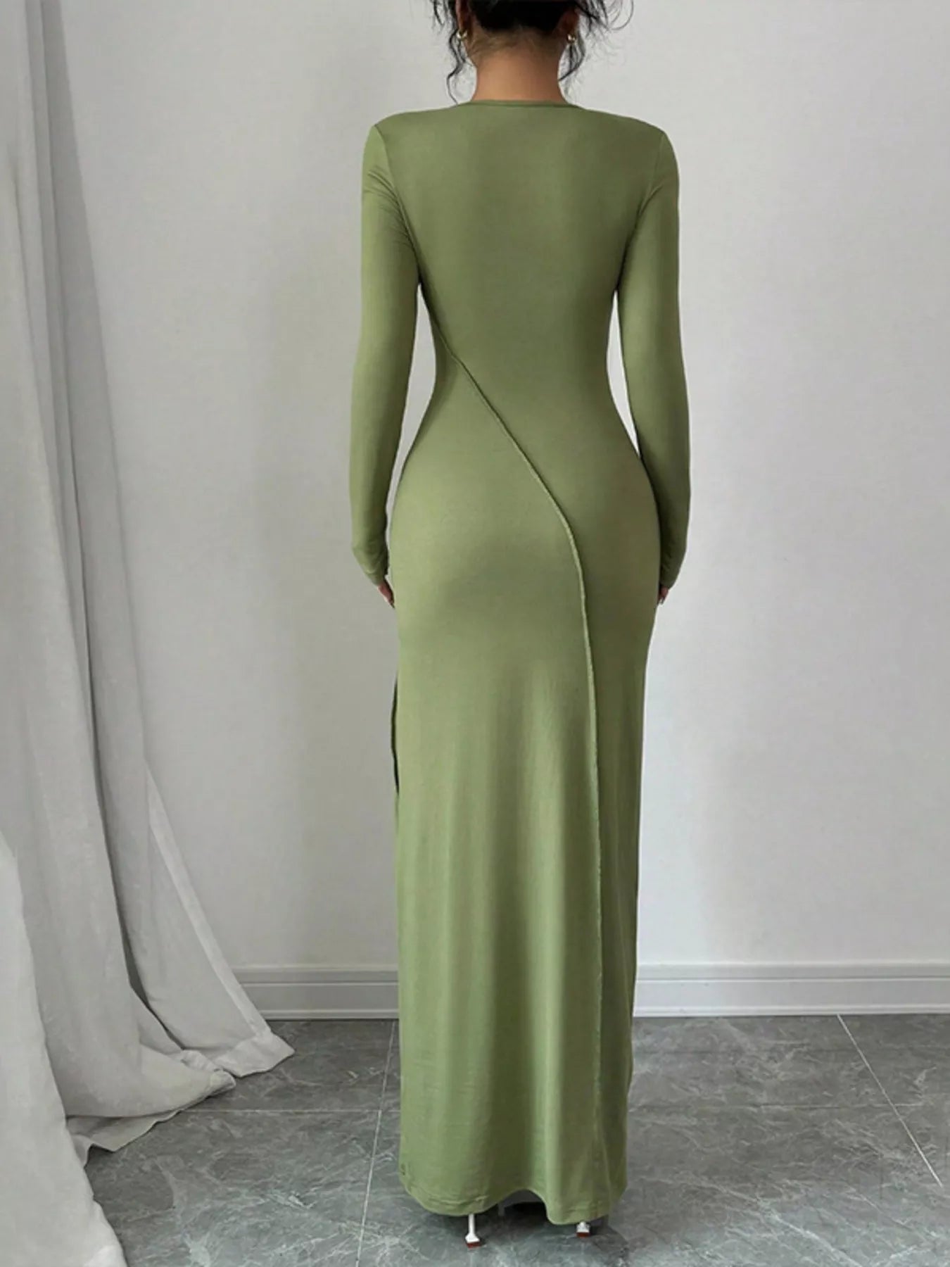 Green long-sleeve dress worn by a person against a plain background