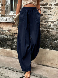 Person wearing navy blue wide-leg pants standing against a textured wall.