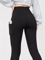 Black high-waisted leggings with a side pocket holding a phone, shown on a model from the back wearing a light gray sweatshirt against a white background.