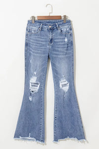 Distressed blue jeans on a hanger against a white background